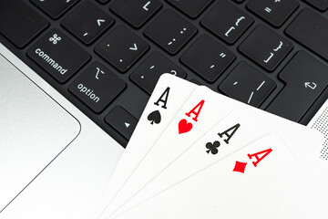 Close-up image of playing cards on a laptop keyboard, featuring Aces and King of Spades suggestive of a royal flush in poker The scene implies technology, gaming, and strategic thinking