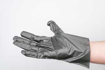 Close-up of a snugly fitted black rubber glove on a fair-skinned adult hand against a neutral background, photographed in an informative style