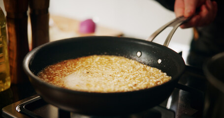 Cooking, pan or risotto with hand in kitchen of restaurant closeup for diet, health or nutrition. Gas stove, ingredients and rice with chef person in hotel for gourmet cuisine, hospitality or service