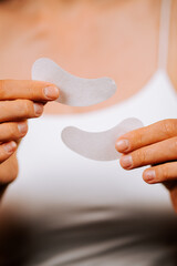 Beauty woman applies under eye collagen pads for refreshed skin in studio setting