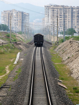 Freight Train on Railway Tracks Approaching Urban Skyline