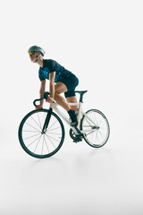 Low angle dynamic image of focused man, cyclist in full gear in motion, cycling, training isolated on white background. Concept of sport, competition, active lifestyle, endurance