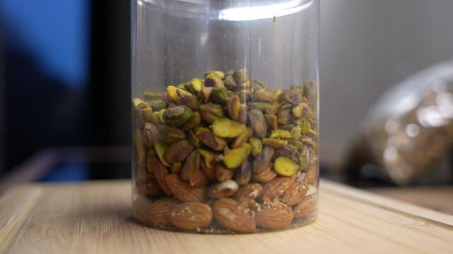 Macro shot of mixed nuts filling plastic jar. Healthy vegan snack