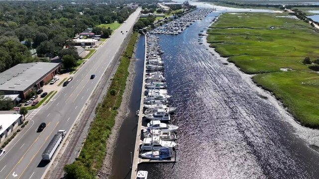 Boats docked in Marina at Brunswick, Georgia beside public park and inlet waterway with salt water tidal marsh 