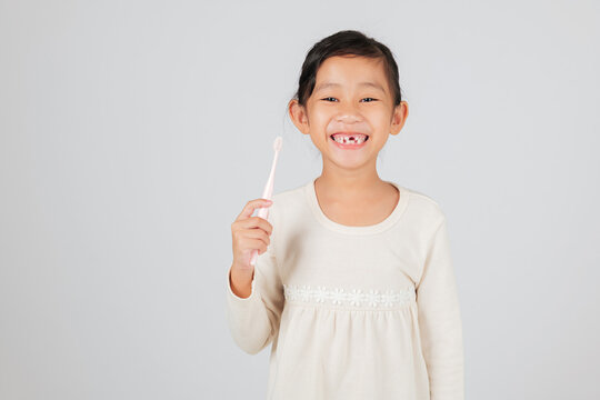 A kid with a missing tooth holds a toothbrush happily. The dentist discusses tooth loss, helping children learn a good dental care routine for healthy teeth. isolated white background
