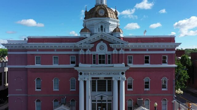 A vibrant rising aerial perspective showcases the architectural beauty of Berkeley County Courthouse in Martinsburg, West Virginia, surrounded by lush greenery and clear skies.