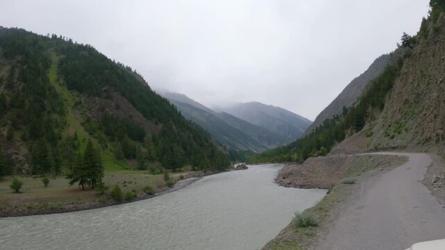 4k POV shot of a vehicle drive besides the river Chenab during a cloudy day as seen on the way to Udaipur in Pattan Valley, Lahaul, Himachal Pradesh, India. Scenic drive besides the river in Himalayas