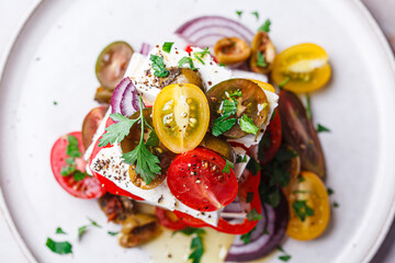 Greek salad stack with feta cheese, tomatoes, red onions and olives.