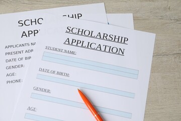 Obraz premium Scholarship application forms and pen on wooden table, above view