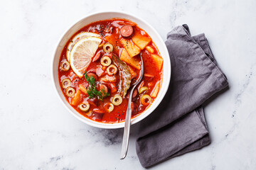 Traditional soup solyanka with smoked sausages, olives and potatoes.