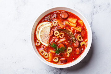 Traditional soup solyanka with smoked sausages, olives and potatoes.