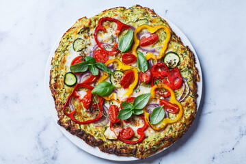Vegan pizza on zucchini crust with vegetables and mozzarella.