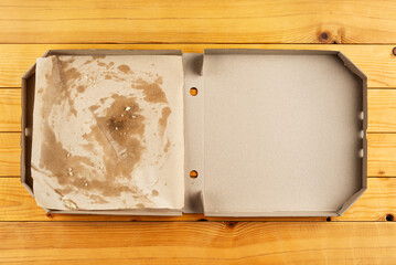 Pizza box with breadcrumbs on natural wooden table flat lay view