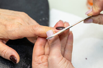Nail care procedure in a beauty salon. Female hands and tools for manicure, process of performing...