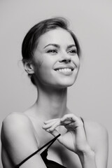 Obraz premium Smiling young woman with natural makeup forming a heart shape with her hands, expressing joy and positivity. Emotional and intimate portrait concept.