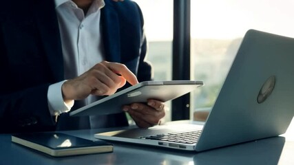 Close-up of businessman using laptop and tablet in office, multitasking and digital work concept - Powered by Adobe