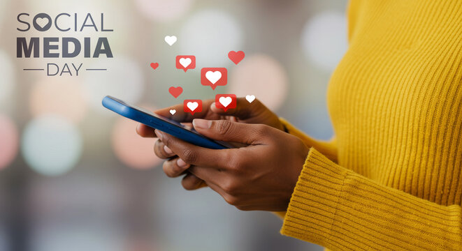 Black woman in yellow sweater interacting with a phone showing heart notifications for Social Media Day