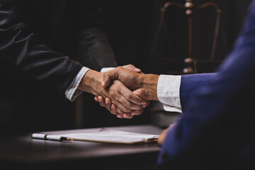 Lawyers shaking hands after signing contract in law office.