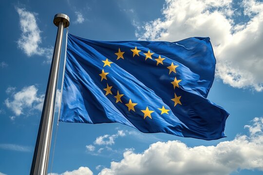 European Union flag waving against a clear blue sky with fluffy clouds in the background during a sunny day