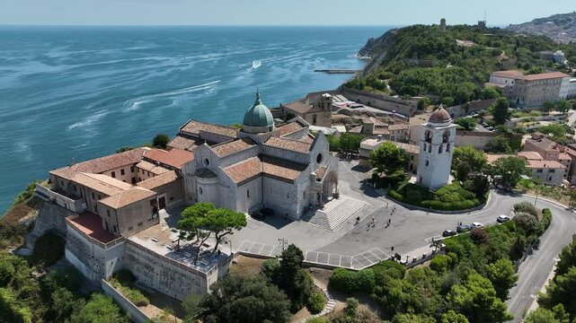 Aerial drone footage of the Ancona Cathedral (Cattedrale di San Ciriaco) overlooking the Adriatic Sea. Stunning panoramic view of the historic church on the hilltop with the sea and coastal cityscape 