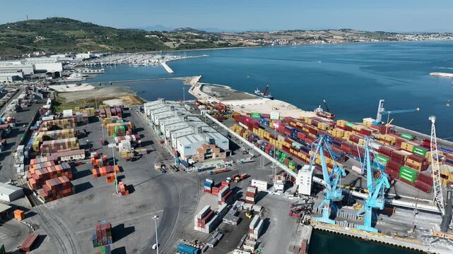 Aerial 4K video of the commercial port of Ancona, showing cranes, trucks, and stacked shipping containers.