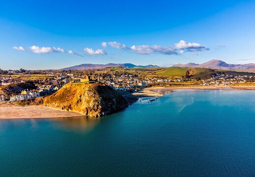 An aerial view towards the town and ruins of the castle above Criccieth, Wales in springtime