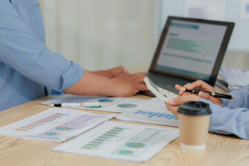Corporate professionals in a strategy meeting analyzing charts and financial data, showcasing themes of business consulting, teamwork, and leadership development.