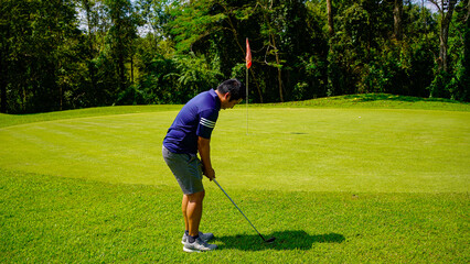 Golfer playing golf in the evening golf course, on sun set evening time.