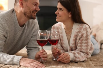 Happy couple with glasses of wine on floor at home