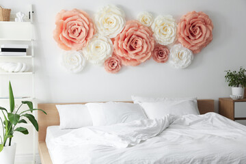 Beautiful decorative paper flowers on wall in bedroom