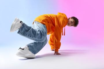 Boy in stylish clothes dancing on color background