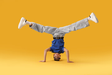 Boy in stylish clothes dancing on orange background
