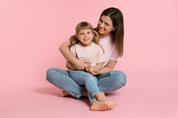 Happy mother and her cute daughter on pink background