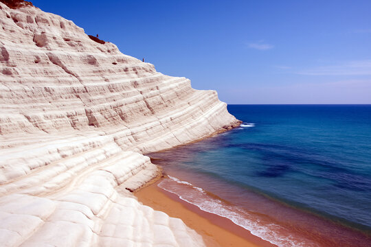La monumentale Scala dei Turchi sulla costa siciliana: quando la marna bianca scolpita in gradoni naturali dal vento e dal mare si staglia con abbagliante candore contro l'azzurro intenso del Mediterr