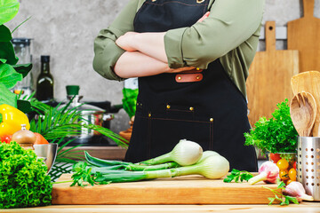 Cook holds arms crossed over chest. Cooking food in the kitchen. with wooden table, kitchenware,...