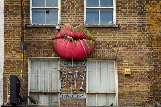 Bold red lips holding a cigarette sculpture on the facade of Compendium Jewellery in Camden, London &mdash; an iconic and edgy artistic storefront