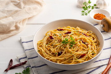 Homemade Spaghetti Aglio e Olio with Garlic ,chili flakes ,Oil ,fresh parsley and Parmesan Cheese in white plate.