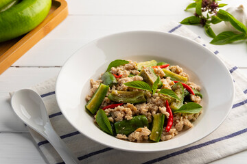 Asian style clean food.Stir fried long green eggplant with ground chicken breast and basil leaves in white plate.