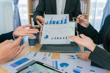 Working and brainstorming on financial and investment ideas for new business projects to discuss and analyze charts and graphs, using a pen to point to specific data points on a nearby document.