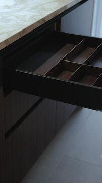 Close-up of a woman's hand opening an empty kitchen drawer. Stylish kitchen with marble countertops. Vertical video