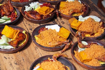Ayam Bakar Madu, Roasted Chicken with Honey with chili sauce, tofu, vegetables served on a wooden plate. This food is typical of Indonesia.