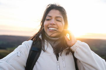Smiling hiker enjoys sunset view on a scenic mountain with light breeze in the air during an...