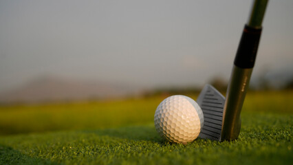 Golf clubs and balls on a green lawn in a beautiful golf course with morning sunshine.