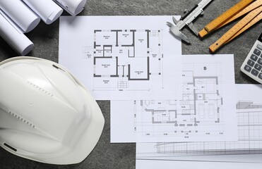 Different architectural drawings, hard hat, folding ruler, calculator and vernier caliper on grey...