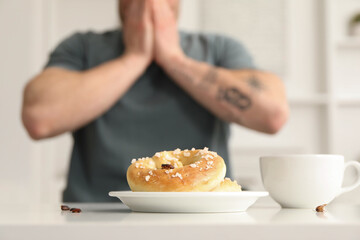 Shocked young man looking at cockroaches and pretzels on white table indoors, selective focus. Pest problem