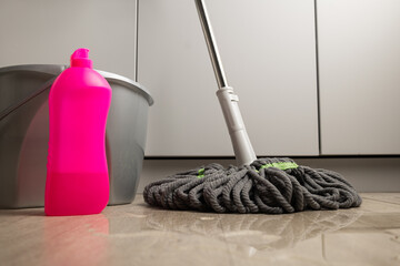 A floor-cleaning mop next to a bucket of water and detergent with spilled water. The concept of cleaning the home and office. © Лариса Андреева
