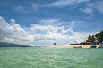 The sea on the island has beautiful clouds in the sky.