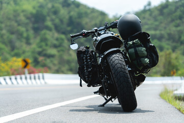 A motorcycle with gear parked on an open road, surrounded by green hills and a curving highway.