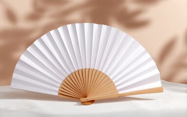 Elegant white paper fan displayed on a textured surface with soft shadows in the background