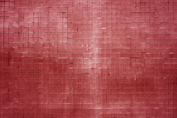 Grungy wall made of small red square tiles.